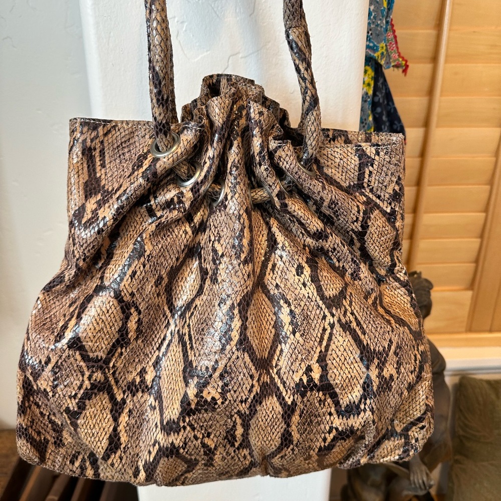 Faux python handbag with spacious bucket compartment and durable construction.